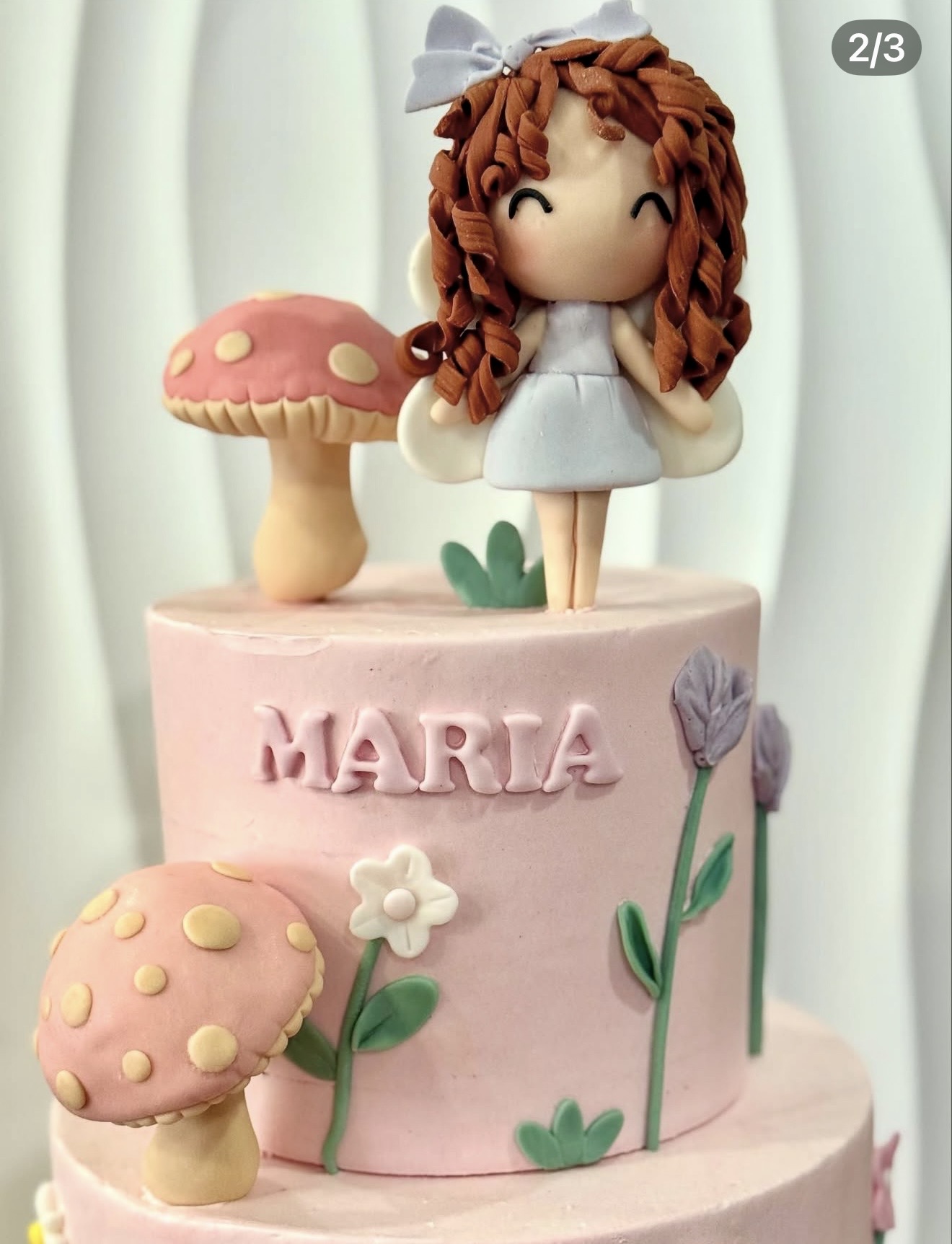 Boneca Encantada — Bolo rosa delicado com boneca de caracóis modelada, cogumelos e flores em pasta de açúcar.